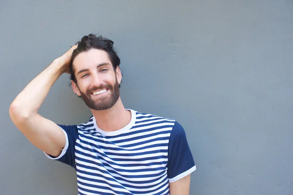 Schöner junger Mann lächelt mit der Hand im Haar — Stockfoto