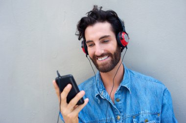 Hareket eden telefon ve kulaklık ile gülümseyerek mutlu bir adam 