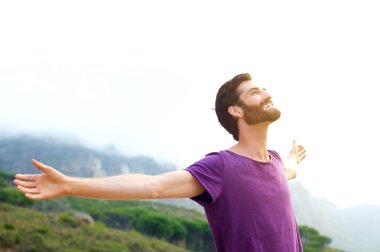 Mutlu genç adam silah ile doğada ayakta açık yaymak