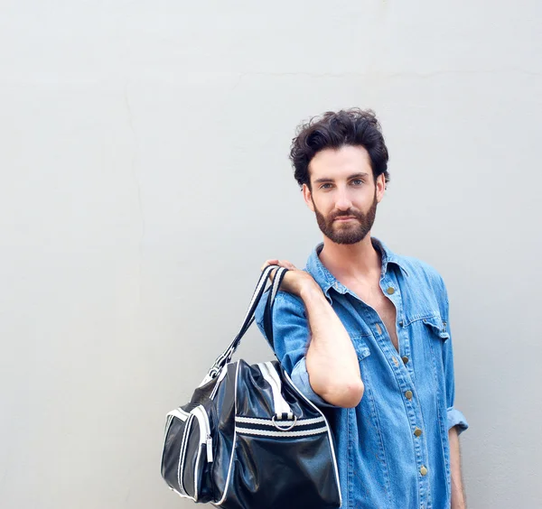 Красивый модник с бородой держит дорожную сумку — стоковое фото