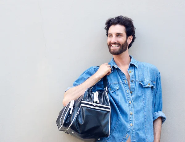 Щасливий чоловік тримає дорожню сумку над плечем — стокове фото