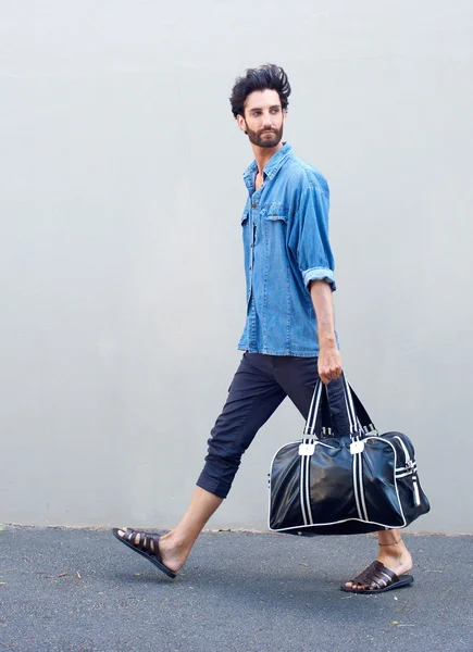 Retrato de vista lateral de un joven caminando con una bolsa de viaje — Foto de Stock