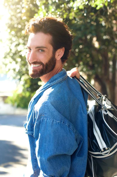 Bonito jovem viajante sorrindo com saco — Fotografia de Stock