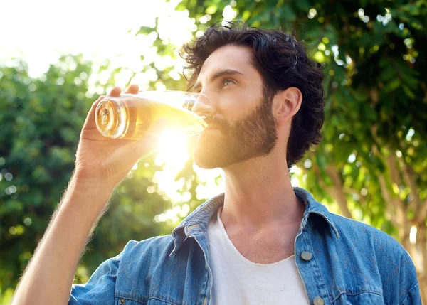 Bello giovane uomo che beve birra in estate — Foto Stock