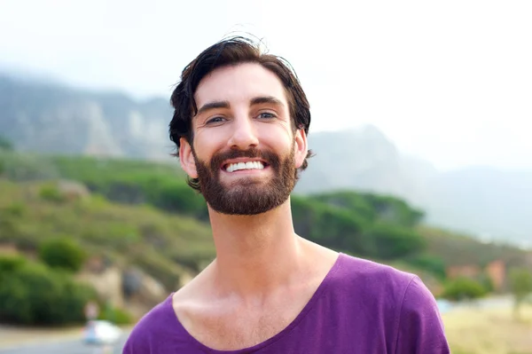 Happy young man with beard smiling outdoors — Stock Photo, Image