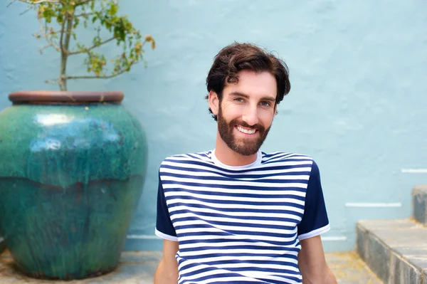 Friendly young man sitting and smiling — Stock Photo, Image