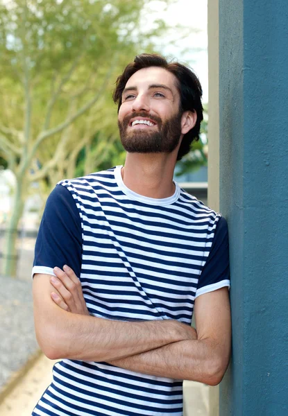 Affascinante giovane uomo sorridente con le braccia incrociate — Foto Stock