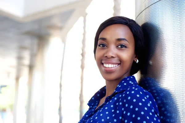 Smiling young woman in blue shirt standing outdoors — Stock Photo, Image