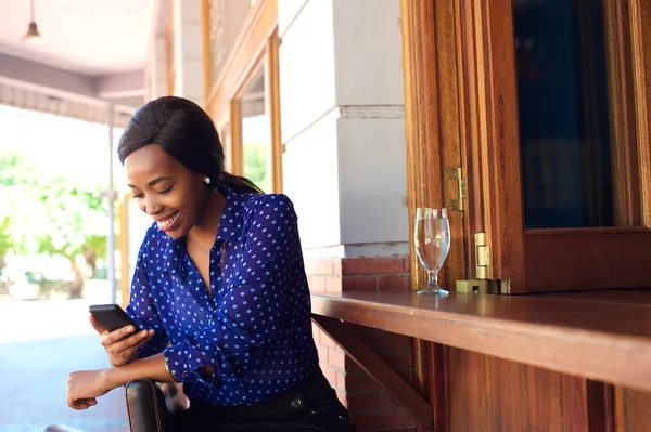 Gelukkige vrouw zitten op bar lachend met mobiele telefoon — Stockfoto