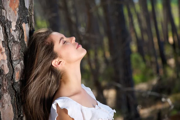 Beautiful girl looking up with eyes closed in the woods — Stock Photo, Image