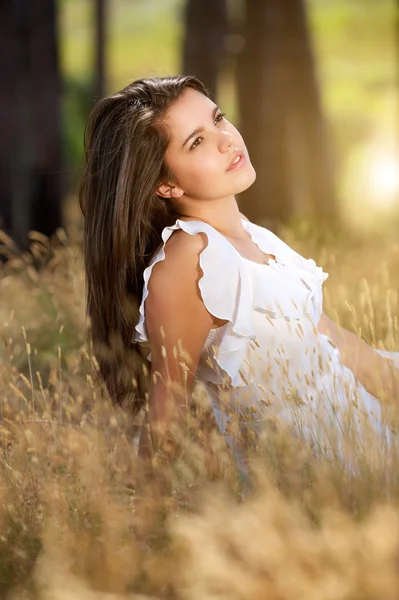 Attractive girl sitting in meadow with white dress — Stock Photo, Image