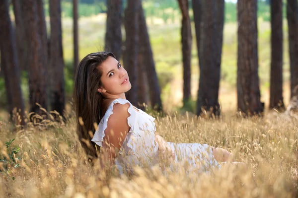 Mooie jonge vrouw zitten in een veld — Stockfoto