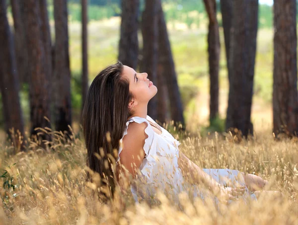 Menina bonita em vestido branco sentado ao ar livre em um prado — Fotografia de Stock