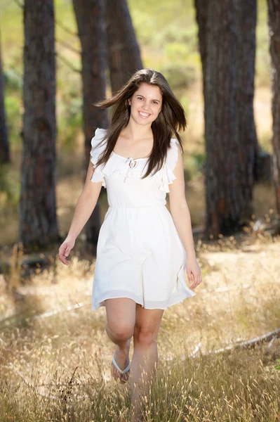 Happy young woman in white dress walking in nature — Stock Photo, Image