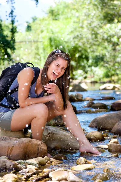 Vrouw wandelaar spatten lachen en water uit stream — Stockfoto