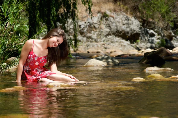 Chica feliz sentado en el agua con vestido rojo — Foto de Stock