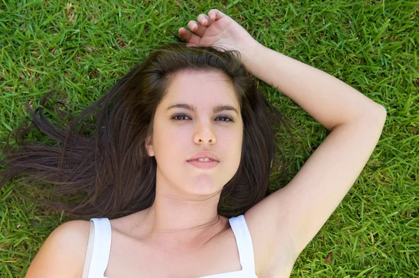Mladá žena ležící na zelené trávě — Stock fotografie
