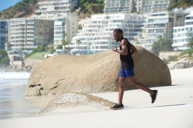 Kumsalda koşan sağlıklı genç adam