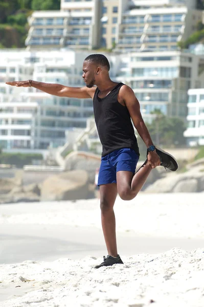 Aktiver Mann dehnt Muskeln am Strand — Stockfoto