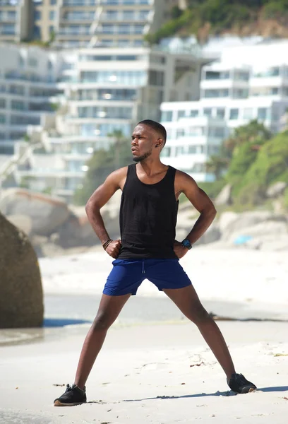 Sportlicher Mann steht in Sportbekleidung am Strand — Stockfoto