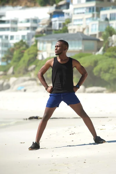 Junger Mann steht am Strand und dehnt sich — Stockfoto