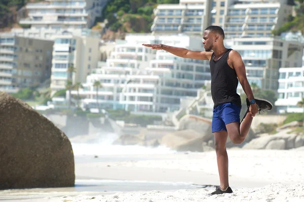 Man exercising leg muscles on the beach — Stock Photo, Image