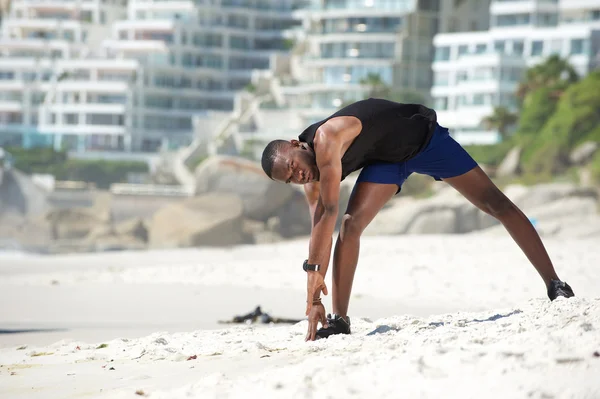 Mann dehnt Beinmuskeln am Strand — Stockfoto