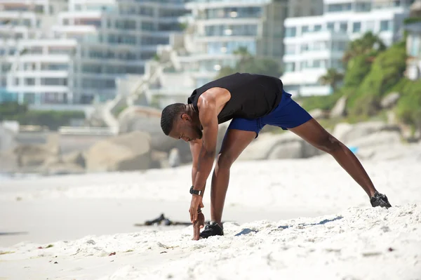 Hombre afroamericano estirando los músculos ejercicio en la playa —  Fotos de Stock