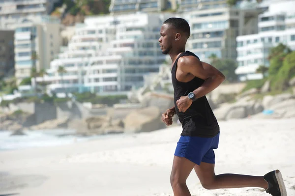 Молодой африканский американец бежит по пляжу — стоковое фото
