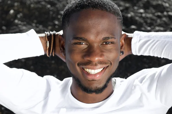 Happy young man smiling with hands behind head — Stock Photo, Image