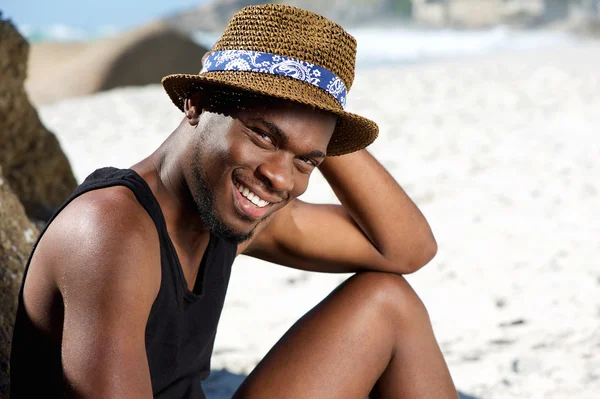 Gülümseyen genç adam sahilde rahatlatıcı — Stok fotoğraf