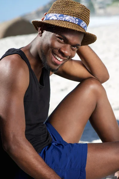 Ontspannen jonge man die lacht op het strand — Stockfoto