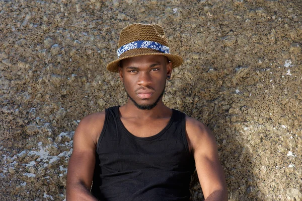 Jovem afro-americano sentado ao ar livre com chapéu — Fotografia de Stock