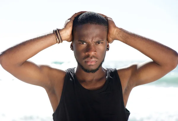 Bonito homem negro posando com as mãos na cabeça na praia — Fotografia de Stock