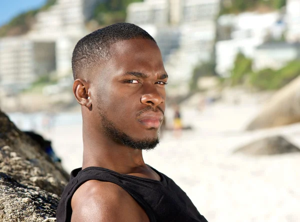 Jovem de pé na praia com expressão séria — Fotografia de Stock