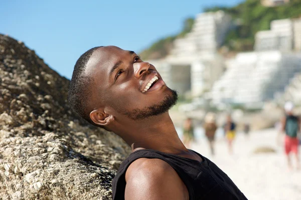 Freundlicher junger Mann lächelt am Strand — Stockfoto