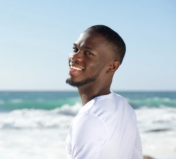 Glücklich lächelnder fröhlicher junger Mann am Strand — Stockfoto