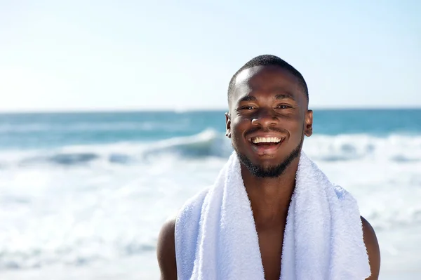 Glücklicher Mann lächelt mit Handtuch am Strand — Stockfoto