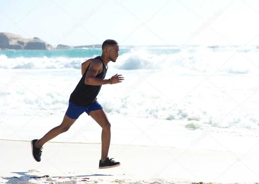 Young athletic man running on the beach