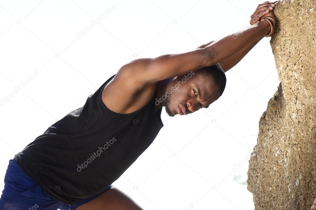 Fitness guy pushing against rock outdoors
