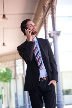 yürüyüş ve cep telefonda konuşurken mutlu işadamı