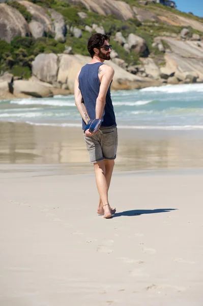 Человек, идущий один по уединенному пляжу с дневником — стоковое фото
