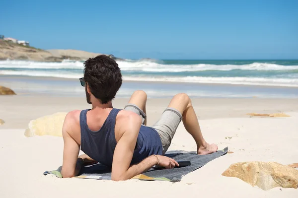 静かなビーチで一人で座っている若い男 — ストック写真