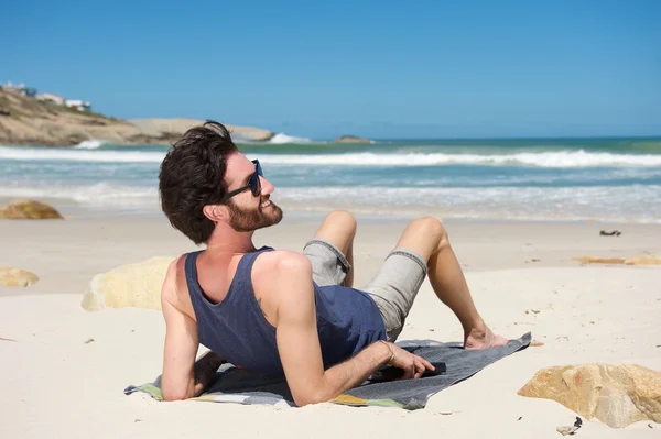 Sorrindo homem sentado na praia isolada — Fotografia de Stock
