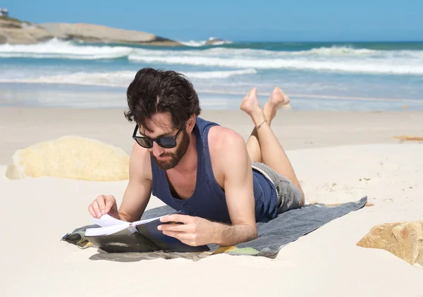 Bello giovane uomo leggere libro in spiaggia — Foto Stock