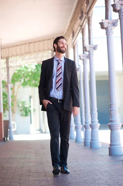 Happy businessman walking outside on sidewalk in the city — Stock Photo, Image