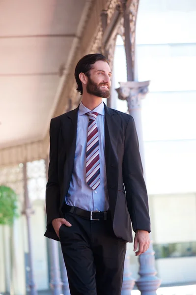 Hombre de negocios sonriente moderno caminando al aire libre — Foto de Stock