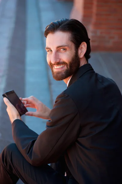 Empresario sonriendo con teléfono celular — Foto de Stock