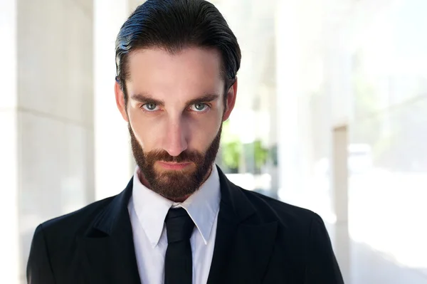 Confident young businessman with beard in black suit and tie — Stock Photo, Image