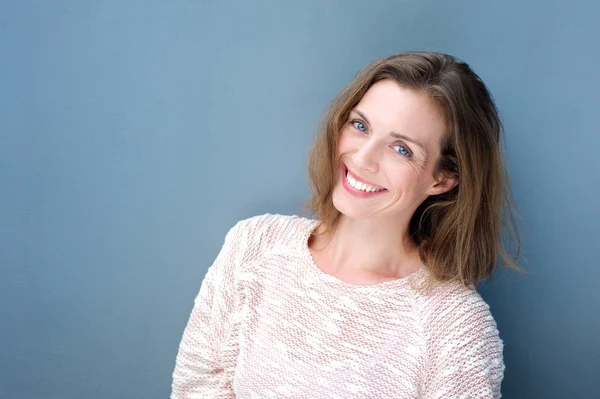 Atractiva sonriente mujer adulta sobre fondo azul — Foto de Stock